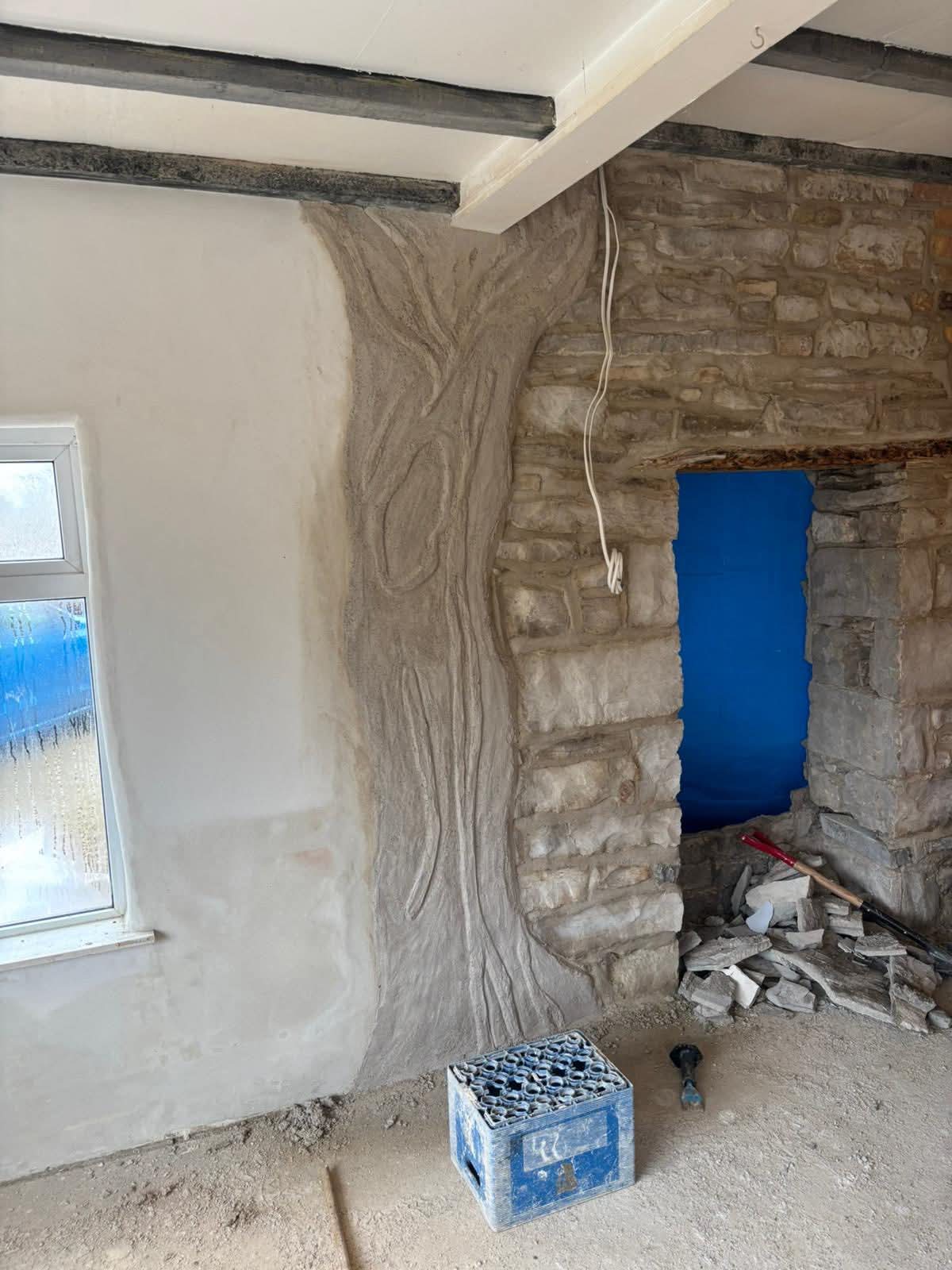 Sculpted lime relief of an ancient tree beside exposed stonework, showing craft skill